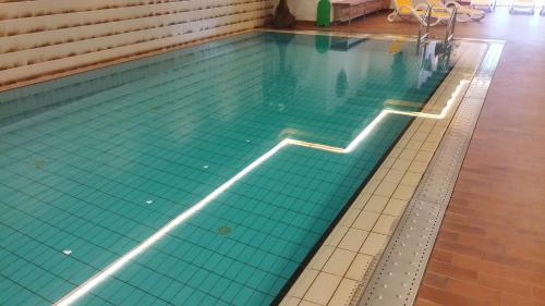 a swimming pool with green tiles on the floor at Hotel Brandl in San Candido