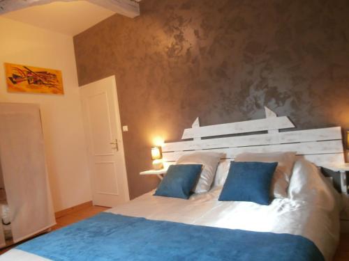 - une chambre avec un grand lit blanc et des oreillers bleus dans l'établissement Au lézard doré, à Lamonzie-Montastruc
