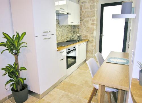 une cuisine avec des placards blancs et une table avec une plante dans l'établissement Appart vieil Antibes, à Antibes