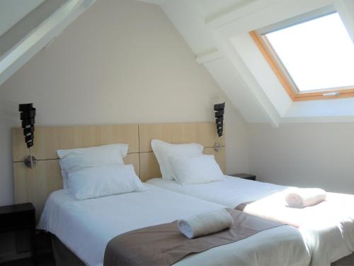 two twin beds in a room with a window at Sweet Home Appart'Hôtel Deauville Sud in Deauville
