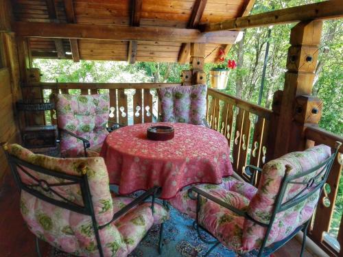 een tafel en stoelen op de veranda aan de achterzijde van een hut bij Apartments DM in Mokra Gora
