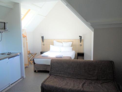 a bedroom with a bed and a couch at Sweet Home Appart'Hôtel Deauville Sud in Deauville