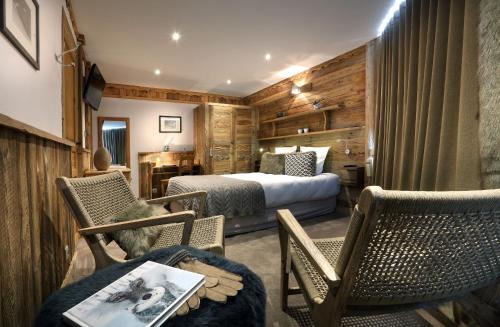 ヴァル・トランスにあるHotel 3 Vallées Val Thorensのベッド、椅子、テーブルが備わるホテルルームです。