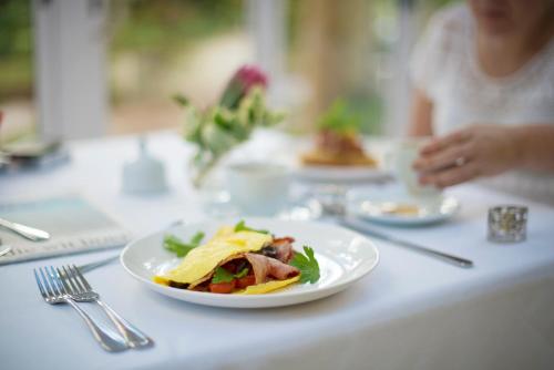 a woman sitting at a table with a plate of food at Last Word Constantia in Cape Town