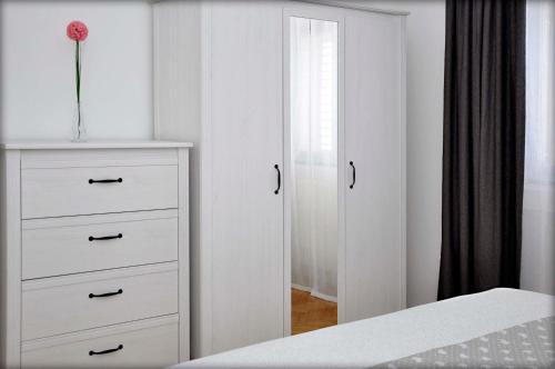 a bedroom with a white dresser with a vase on it at Apartments Barbaresko in Lumbarda