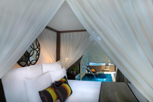 a bedroom with a bed with white curtains and a tub at The Banjaran Hotsprings Retreat in Ipoh