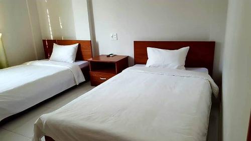 ein Hotelzimmer mit 2 Betten und einem Nachttisch in der Unterkunft Cong Doan Gia Lai Hotel in Pleiku