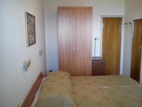 um pequeno quarto com uma cama e um armário de madeira em Room Rubinić em Mošćenička Draga
