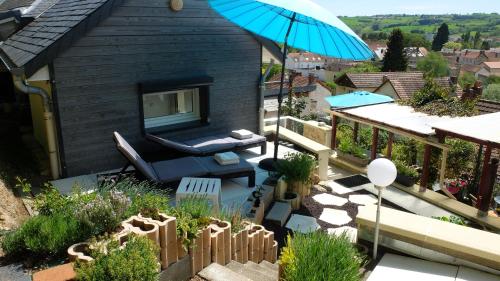 a patio with a blue umbrella and a house at La Cadanise, Suite Étoilée in Saint-Éloy-les-Mines