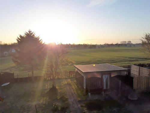 a house in a field with the sunset in the background at Ferienwohnung Stadie in Dörphof