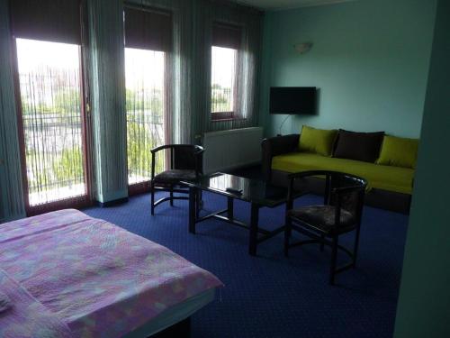 a bedroom with a bed and a couch and a table at Kőrös Hotel in Kiskőrös