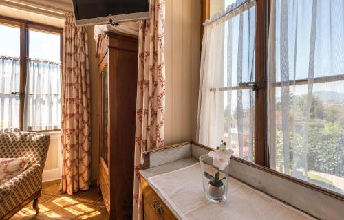 a room with windows and a table with a vase of flowers at Swiss Historic Hotel Masson in Montreux