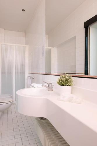 a white bathroom with a sink and a toilet at Hotel Junior by OasiGroup Hotels in Rimini