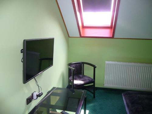 a room with a tv and a chair and a glass table at Kőrös Hotel in Kiskőrös