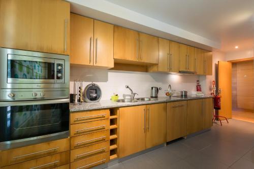 a kitchen with wooden cabinets and stainless steel appliances at Casa do Pico do Salomao in Ponta Delgada
