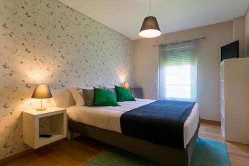 um quarto com uma cama com almofadas verdes em Casa do Pico do Salomao em Ponta Delgada