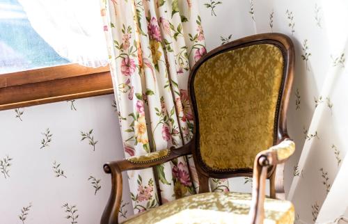 a chair in front of a window with floral wallpaper at Swiss Historic Hotel Masson in Montreux