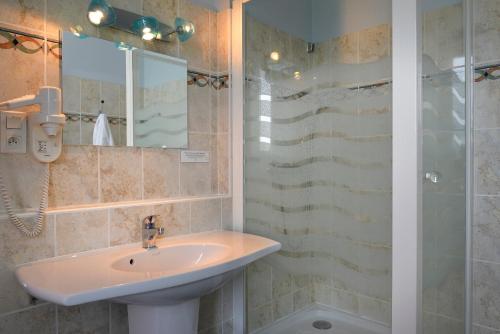 a bathroom with a sink and a shower at Logis Hôtels Restaurant Le Dauphin in Salbris