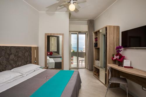 Dormitorio con cama, escritorio y TV en Hotel Romantico, en Gabicce Mare