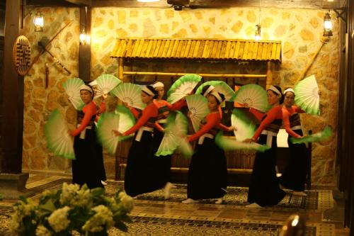 a group of women holding green and white umbrellas at Mai Chau Ecolodge in Mai Chau