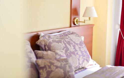 a bedroom with a bed with a pillow and a lamp at Astra Hotel in Klaipėda