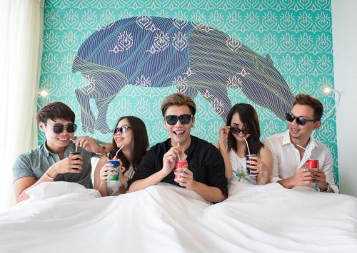 a group of people laying in bed holding their cell phones at Cassia Bintan, part of Banyan Group in Lagoi