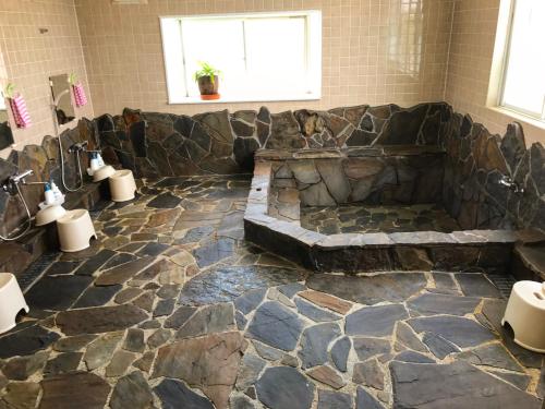a bathroom with a stone floor and a stone tub at Minshuku Yakushima in Yakushima