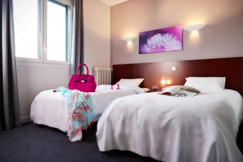 two beds in a hotel room with a pink bag on them at Logis Hotels Grand Hotel d'Orléans in Albi