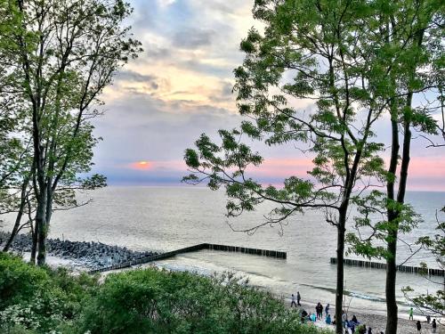 a beach with people standing on the sand and the water at Hotel *** NAT Jarosławiec in Jarosławiec