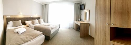 a hotel room with two beds and a television at Hotel *** NAT Jarosławiec in Jarosławiec