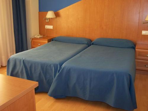 Hotel Estrella del Alemar في لوريدو: سريرين في غرفة الفندق ذات شراشف زرقاء