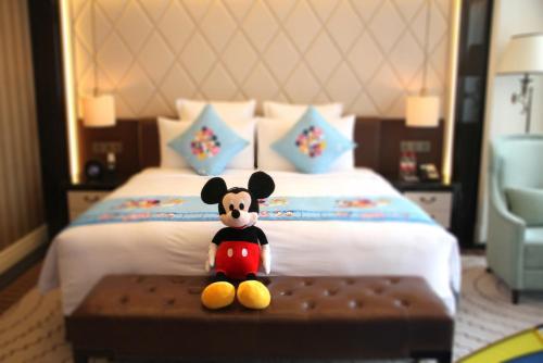 a mickey mouse toy sitting on a table in front of a bed at RenHe Spring Hotel in Chengdu
