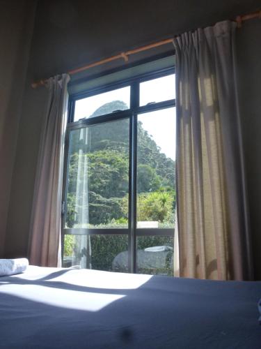 a bedroom with a window with a view of a mountain at Piha Beachstay Accommodation in Piha