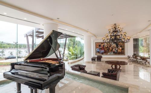 a piano in a living room with a chandelier at Park Regis Goa in Arpora