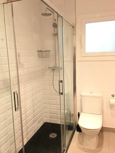 a bathroom with a toilet and a glass shower at Aiguaneu Apartaments Center in Blanes