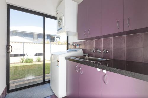 a kitchen with purple cabinets and a sink and a window at The Lane, Doubleview in Perth