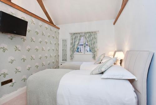 two beds in a bedroom with white walls at Holtby Grange Cottages in York