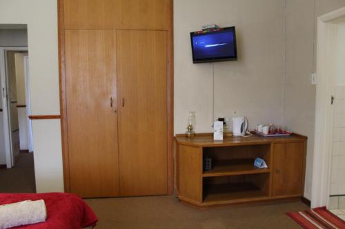 a room with a cabinet and a television on a wall at The Hamlet Country Lodge in Ceres