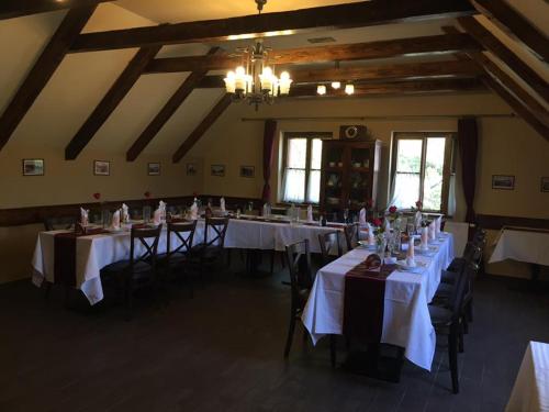 a room with tables and chairs with white tablecloths at Penzion Český Dvůr in Starý Plzenec