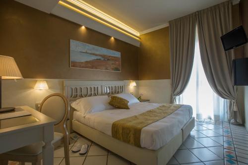 a hotel room with a bed and a desk and window at Hotel Hermitage in Galatina