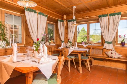 un comedor con mesas, sillas y ventanas en Naturhotel Miraval, en Perca