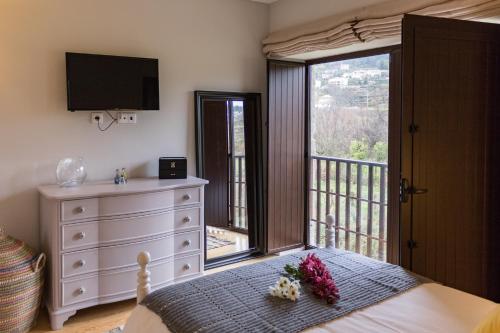 a bedroom with a bed with a dresser and a balcony at Quinta de Alvarenga in Alvarenga