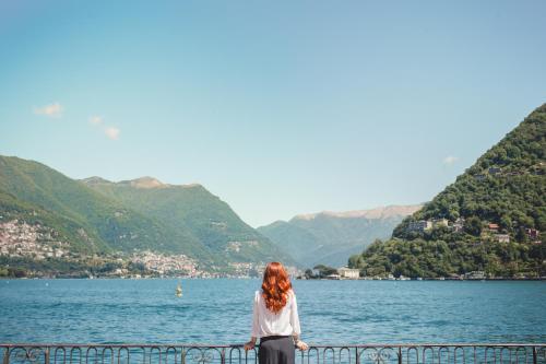 a woman standing on a fence overlooking a lake at Alessia's Place in Como