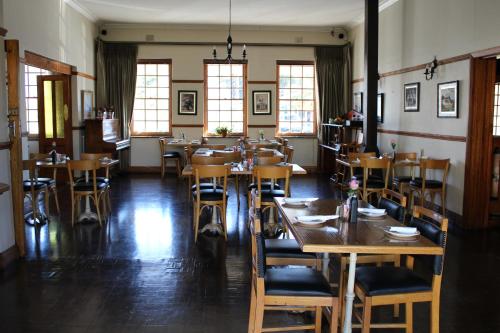 a restaurant with wooden tables and chairs and windows at The Hamlet Country Lodge in Ceres