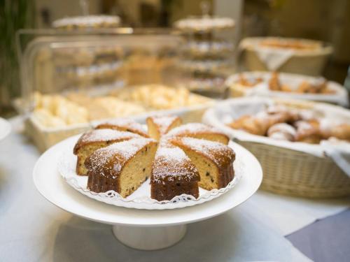 a cake on a plate on a table with other pastries at Hotel Cube in Ravenna
