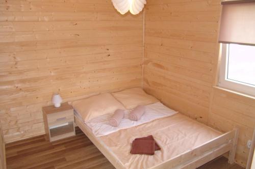 Cette chambre en bois comprend un petit lit et une fenêtre. dans l'établissement Domki Letniskowe u Susła, à Sianożęty
