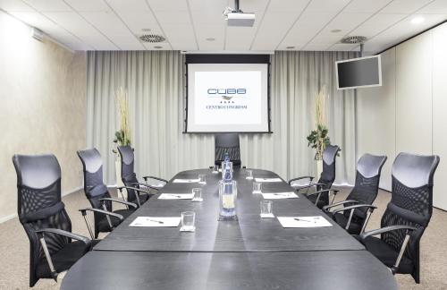 a conference room with a table and chairs and a screen at Hotel Cube in Ravenna