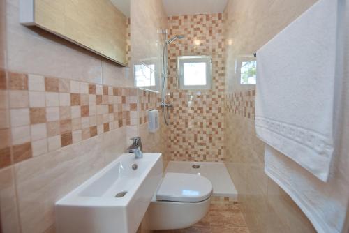 ein Badezimmer mit einem weißen WC und einem Waschbecken in der Unterkunft Villa Ivanovi Dvori in Novalja