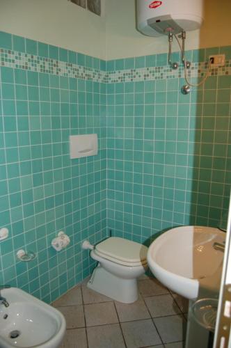 a green tiled bathroom with a toilet and a sink at Solanha monolocale n.4 in Cavo