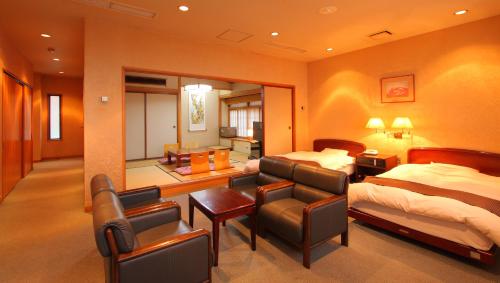 um quarto de hotel com duas camas e uma sala de estar em Kasugai View Hotel em Fuefuki